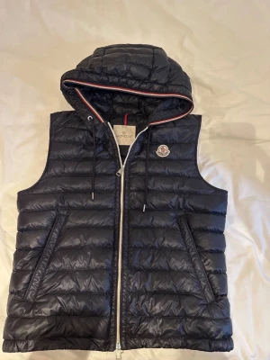 Moncler Cyriaque gilet vest - Sällsyn modell från 2016 som är svår att få tag på.                                                                                               Perefek att ha en sommarkväll eller när det inte är jättevarmt. Är i en mörkblå/svart färg.                 Den är i bra skick och storlek 2 (s/m)                                    Äkta ✅                                                                               Hör av er vid frågor 🙌