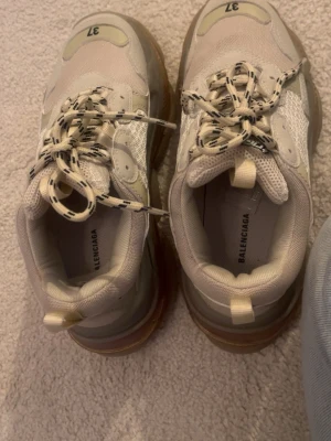  Triple S  sneakers - Chunky  Triple S sneakers med genomskinlig sula och svarta detaljer på snörena. Ovandelen är i mesh och läder med tydlig logga på sidan. Snygg och trendig modell som sticker ut med sin robusta design och coola detaljer.