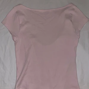 Ljusrosa topp med öppen rygg - Supersöt ljusrosa topp med en snygg öppen rygg. Modellen är tight och croppad. Enkel men ändå unik med den djupa ryggen. Ny med prislapp 