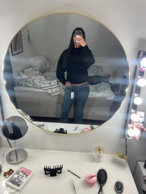 Blå bootcut jeans från Gina Tricot - Säljer ett par blå bootcut jeans från Gina Tricot med klassiska vita sömmar och snygga detaljer på bakfickorna. Jeansen har låg midja och är tillverkade i denim med stretch för en bekväm passform.  