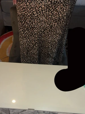 Svart långkjol med blommigt mönster - Långkjol i svart med små blommiga mönster i vitt och beige. Kjolen har rak passform och är tillverkad i ett lätt och mjukt material som faller snyggt. Perfekt för dig som gillar en avslappnad men ändå trendig stil. Skulle säga liten i storlek en stretchig. Dragkedja på sidan. Jag är 162cm. 