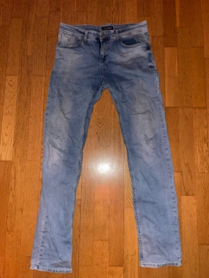 Ljusblå slim fit jeans från Armani - Snygga ljusblå slim fit jeans från Armani med klassisk femficksdesign och normal midja. Jeansen har en lätt tvättad look och raka ben, perfekta för en avslappnad stil. Materialet är mjukt och stretchigt för extra komfort. Riktigt schyssta. 
