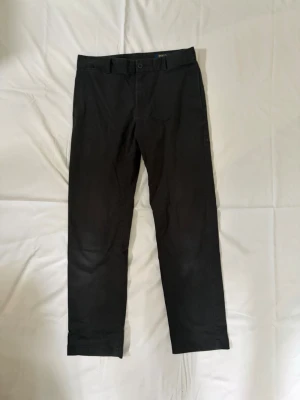 Svarta kostymbyxor från Polo Ralph Lauren - Säljer ett par stilrena byxor från Polo Ralph Lauren i mörk marinblå färg. Klassisk och tidlös modell som passar både uppklätt och casual. Diskret röd broderad Polo-logga baktill och rak passform. Märke: Polo Ralph Lauren Storlek: M Färg: Marinblå / svartblå Modell: Chinos / dressade byxor Skick: Bra skick, normal användning Detaljer: Knäppning bakfickor, broderad logga, stilren passform Perfekta till både skjorta, hoodie eller stickat för en clean preppy/vintage look.