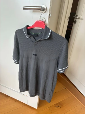 Grå pikétröja från BOSS - Knappt använd Hugo boss tröja i mycket bra skick. Storlek S. Limiterad upplaga