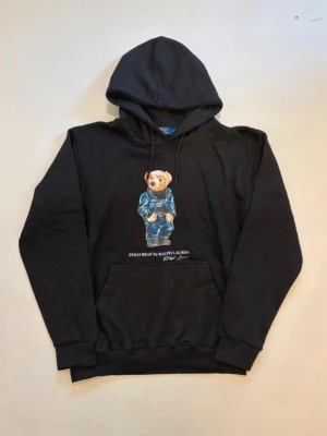 Ralph lauren björn hoodie L - Svart Ralph Lauren polo bear hoodie //  Storlek L //  Mått   Längd  68cm  Axelbredd  53cm  Bredd mellan armhålorna 54cm  Armlängd  62cm Mycket bra skick aldrig använd //  Skriv vid minsta fråga eller fundering💯