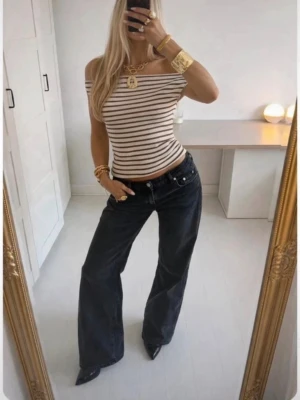 Svarta vida jeans med låg midja - Säljer ett par svarta jeans med vida ben och hög midja. Jeansen har klassisk femficksdesign, bälteshällor och är gjorda i kraftig denim. Perfekta för en trendig och avslappnad look. (De är några cm uppsydda, då de var långa i modellen). 💞💞