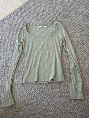 Ljusgrön ribbad långärmad topp - Säljer en ljusgrön ribbad topp med lång ärm och rundad halsringning. Perfekt för dig som gillar en enkel och stilren look. Materialet är mjukt och stretchigt, vilket gör den bekväm att bära hela dagen.