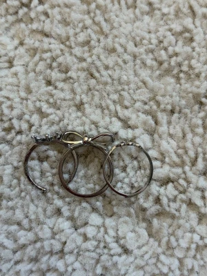 Söta silverringar med rosett - Tre tunna silverfärgade ringar, varav en har en söt rosett med gnistrande stenar. Perfekt för dig som gillar stilrena och feminina accessoarer. Passar att bära tillsammans eller var för sig för en personlig look.