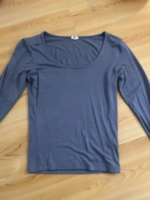 Ljusgrå långärmad topp - En enkel och stilren ljusgrå långärmad topp med rund halsringning. Tillverkad i mjukt bomullsmaterial som känns skönt mot huden. Perfekt att matcha med jeans eller kjol för en clean look. Armarna är lite insydda för dom va lite pösiga.
