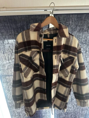 Bershka overshirt/jacka - Rutig jacka från Bershka  Beige/brun/vit jacka i fint skick. Knappar framtill och fickor. Perfekt till höst/vår 🍂