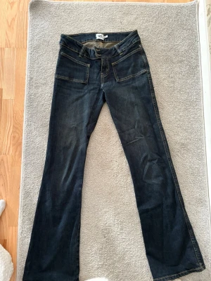 Mörkblå bootcut jeans från 157 - Snygga mörkblå jeans från 157 med bootcut passform och klassiska fickor fram och bak. Jeansen har kontrastsömmar och är tillverkade i denim med lite stretch för extra komfort. Perfekta för dig som gillar en avslappnad och trendig look.