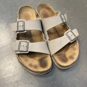 Brikenstock Arizona  - Säljer ett par Birken i populära modellen Arizona. Dem är i fint skick med inga defekter. Knappast använda dessutom. Dem är i storlek 46 och har en lite snyggare grå färg. Perfekt nu till sommaren.