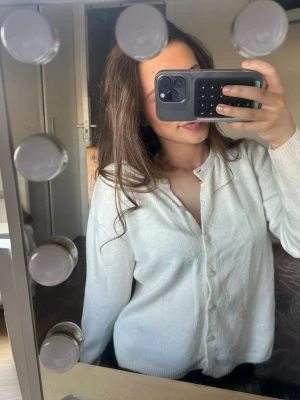 Vit basic kofta med knappar - Säljer en enkel och stilren vit kofta med knäppning framtill. Koftan har långa ärmar, rund halsringning och mjukt material som känns skönt mot huden. Perfekt att slänga över en topp för en clean look.