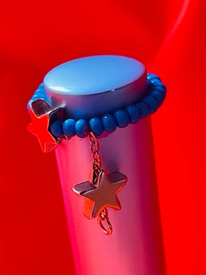 By prisförslag- turkos pärlring med stjärnhängen one size - Cool ring med små turkosa pärlor och två guldiga stjärnhängen. Ringen är elastisk och har en lekfull design som sticker ut. Perfekt för dig som gillar färg och unika detaljer. Stjärnorna hänger i en liten kedja för extra effekt. Den går att få i vita pärlor och silver stjärnor också. 