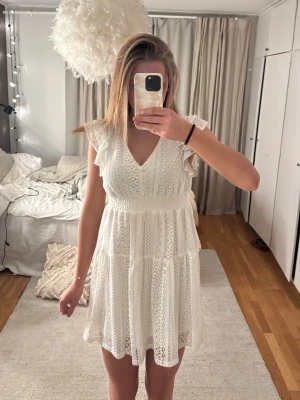 Vit spetsklänning med volangärmar - Söt vit kortklänning i spets med v-ringning och volangdetaljer vid ärmarna. Klänningen är perfekt för sommarens alla tillfällen. Luftigt material och fina detaljer gör den extra speciell. Använd en gång och känns som ny💓 