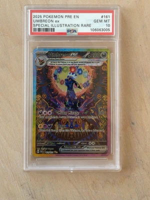 Umbreon ex Pokémonkort PSA 10 - Obs vet ej om kortet är orginsl köptes begagnad. Säljer ett Umbreon ex special illustration rare Pokémonkort, graderat PSA 10 GEM MT. Kortet har färgstark holografisk design med Umbreon i centrum och flera energisymboler runtom. Kortet är inneslutet i ett genomskinligt PSA-fodral.
