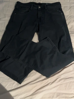 Svarta jeans från Replay - Snygga svarta slim fit jeans från Replay med klassisk femficksmodell och raka ben. Jeansen har en diskret logga på bakfickan och patch med Replay-märke i midjan. Skriv om ni undrar något