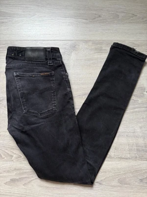 Nudie jeans  - Säljer nu ett par väldigt snygga  svarta nudie jeans i storlek W32 L34. Jeansen har ett litet slitage längst ner vid byxorna annars så är de i väldigt bra skick. Vid fundering är det bara att hojta till !