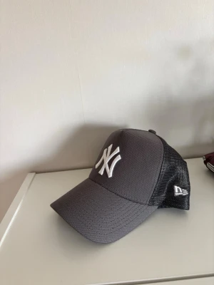 Grå New Era NY keps mesh - Säljer en grå keps från New Era med vit NY-logga framtill och svart mesh på sidorna och bak. Klassisk böjd skärm och justerbar snapback. Hör av er vid frågor! Priset går att diskutera 