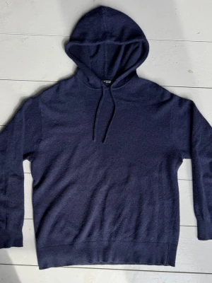 Cashmere hoodie - En stilren mörkblå hoodie från Zara i bomull. Tröjan har en klassisk huva med dragsko och ribbade muddar vid ärmslut och nederkant. Endast litet hål som sytts igen, syns knappt se bild 4-5. Perfekt för dig som gillar enkel och tidlös design. Pris ej hugget i sten, tveka inte att höra av er vid frågor eller annat pris!