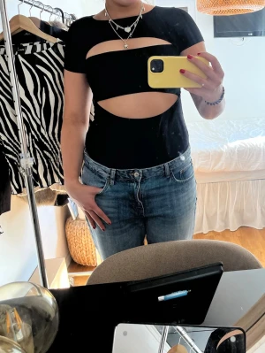 Svart cut out body från New Yorker - Snygg svart body från New Yorker med korta ärmar och coola cut out-detaljer framtill.