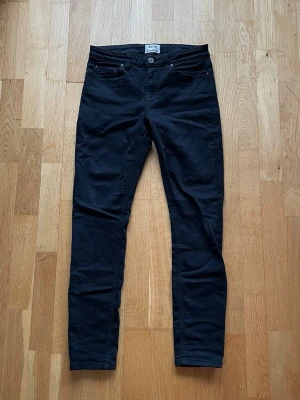 Svarta skinny jeans från Acne Studios - Säljer ett par svarta skinny jeans från Acne Studios. Klassisk femficksmodell med smal passform och normalhög midja. Jeansen har bälteshällor och knappgylf. Perfekta för en stilren och modern look.