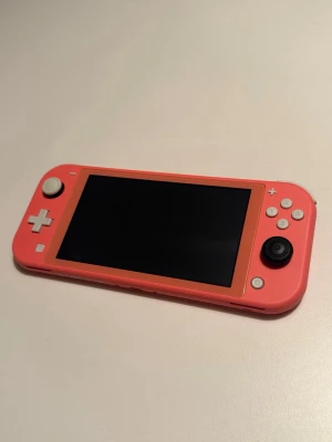 Nintendo Switch Lite med väska och hållare - Säljer en Nintendo Switch Lite i snygg korallrosa färg. Följande ingår: konsol, laddare, väska och ett spelfäste. Den är i mycket fint skick. 