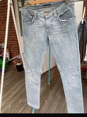 Ljusblå jeans från Nudie Jeans - Säljer ett par ljusblå jeans från Nudie Jeans med klassisk femficksmodell och raka ben. Jeansen har en snygg tvättad look och är tillverkade i bomull. Perfekta för dig som gillar en avslappnad och stilren stil.
