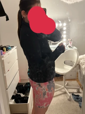 Färgglada cykelshorts i rosa och grått - Säljer ett par trendiga cykelshorts med färgstarkt mönster i rosa, grått och vitt. Shortsen har en tight passform och är perfekta för träning eller en sportig look. Materialet är stretchigt och bekvämt, vilket gör dem lätta att röra sig i.