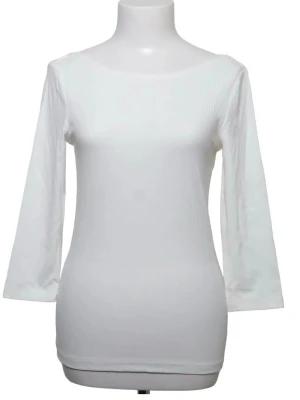 Vit ribbad topp med 3/4-ärm - Snygg vit ribbad topp med trekvartsärm och rund halsringning fram samt djupare urringning i ryggen. Figurnära passform som passar perfekt till både jeans och kjol. Enkel och stilren design som är lätt att matcha. Nypris 260