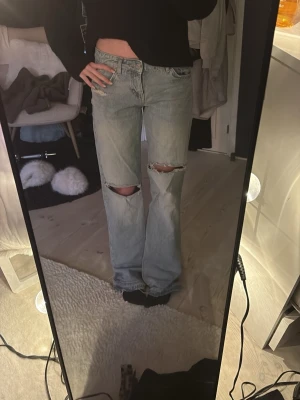 Zara jeans - Säljer ett par ljusblå jeans med raka ben och slitningar över båda knäna. 
