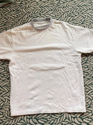 Acne Studios Mock Neck T-Shirt Vit - Vit oversized T-shirt från acne studios med text runt kragen. Perfekt för layering. Storlek S. Säljer då jag inte använder. 