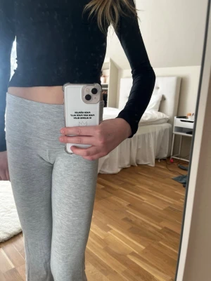 Ljusgrå ribbade leggings - Säljer ett par ljusgrå leggings med ribbad struktur och hög midja. De är stretchiga och sitter tight, perfekta för en avslappnad och trendig look. Passar till crop tops och hoodies. Materialet känns mjukt och följsamt.