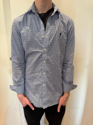 Blå vit rutig Ralph Lauren skjorta - Säljer en snygg blå vit randig Polo Ralph Lauren skjorta i storlek S. Modellen på bilden är 181 cm och väger 66 kg.