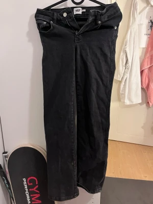 Svarta raka jeans från 157 - Säljer ett par svarta jeans från 157 med raka ben. Silverfärgade färgade knappar och detaljerade bakfickor med lock och knapp. Materialet är denim med en mjuk känsla och passar perfekt till en avslappnad stil. Står även att det är i längd short, men de är för långa på mig som är 155. När man har på sig de blir det som att de är bootcut.
