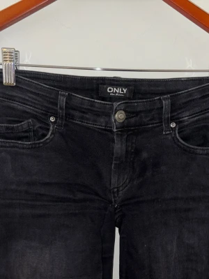 Svarta ripped jeans från ONLY - Säljer ett par svarta jeans från ONLY med slitningar på båda benen. Jeansen har klassisk femficksmodell, knappgylf och är tillverkade i stretchigt denimtyg för skön passform. De är mer lågmidjade än vanliga jeans från only.