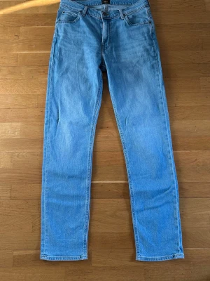 Ljusblå jeans från Lee - Säljer ett par klassiska ljusblå jeans från Lee med rak passform. Jeansen har normal midja och Lee-logga på bakfickan. Tillverkade i slitstark denim med snygg tvättad look. Perfekta för en avslappnad stil. Storlek W31, L34