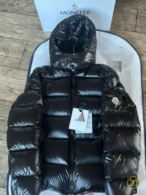 Svart dunjacka från Moncler - Snygg svart dunjacka från Moncler med glansig finish och klassisk puffer-design. Jackan har huva, dragkedja framtill, två sidofickor med dragkedja och Moncler-logga på ärmen. Perfekt för kalla vinterdagar och riktigt trendig stil.jackan är äkta Original. Mått är längd 66-67cm  bredd 58-60cm ja skulle kunna går med på att byta jackan mot en samsung s25 ultra eller en annan telefon i nyskick för samma pris..