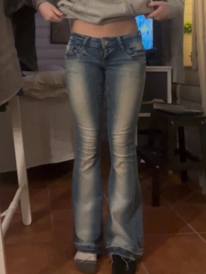Blå bootcut jeans - Snygga blå bootcut jeans med en lätt tvättad look. Köpta från gina men säljer då jag har tappat bort kvittot så kan inte lämna tillbaka. Jag har även sprättat upp dem vid fötterna och lagt till coola nitar på bakfickorna. Midjemåttet är 36cm och innebenslängden är 79cm.