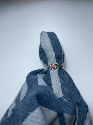 Pandora silverring med rosa sten - Söt silverring från Pandora med en rosa sten i mitten och små detaljer runt om. Ringen är tillverkad i 925 sterling silver och har en romantisk, blommig design som sticker ut. Perfekt för dig som gillar unika smycken med färg. Från Disney kollektionen skönheten och odjuret