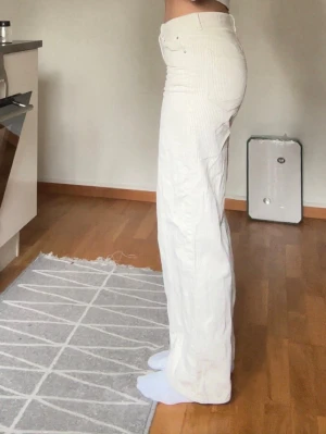 Vida vita manchesterbyxor - Säljer ett par snygga vita manchesterbyxor med hög midja och raka, vida ben. Byxorna har klassiska fickor fram och bak samt bälteshällor. Perfekta för dig som gillar en clean och trendig look. Materialet är mjuk manchester som ger en skön känsla.