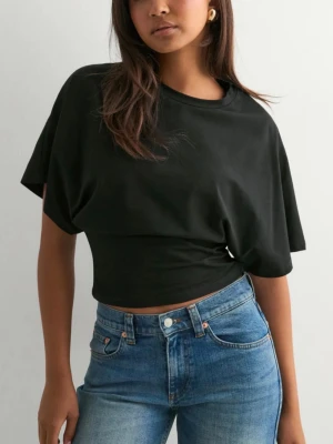 Svart croppad t-shirt - Svart croppad t-shirt med lös passform i ärmarna, men indragen midja och korta ärmar. Tillverkad i mjuk bomull som känns skön mot huden. Perfekt till jeans eller kjol för en avslappnad look, eller till en kjol på middag 