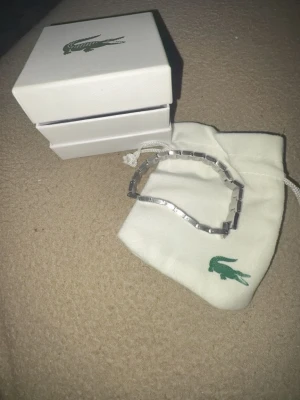 Silverfärgat armband från Lacoste - En jätte fin Lacoste armband för billigt pris! Kom på me bud