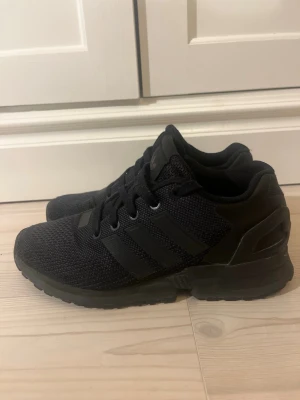 Svarta Adidas Torsion  - Säljer ett par helsvarta Adidas Torsion sneakers med klassiska tre ränder på sidan. Skorna har ovandel i mesh för bra andningsförmåga och en stabil sula i gummi. Perfekta för dig som gillar stilrena och sportiga sneakers. Begränsade utgåva från Adidas Torsion. Priset går att diskuteras.