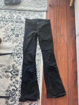 Svarta bootcut jeans från Cheap Monday - Svarta jeans från Cheap Monday med bootcut-modell och klassisk femficksdesign. Jeansen har en diskret lila logotyp på bakfickan och är tillverkade i ett stretchigt denimtyg för en bekväm passform.