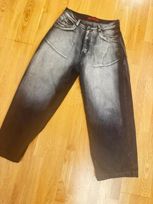 Wide fit jeans från Jaded London - Säljer ett par gråsvarta wide fit jeans från Jaded London med cool faded effekt. Jeansen har raka, vida ben och klassiska fem fickor. Materialet är denim i bomull och de har en modern streetwear vibe. Perfekta för dig som gillar oversized och trendigt.