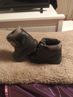 Kängor i strl 21 KAVAT  - Svarta kängor från Kavat i storlek 21 säljes. Skorna är använda utomhus men i gott skick. Normalt slitage förekommer, främst på sulorna, men de är fortfarande hela och fullt fungerande. Inga hål eller skador. Stabila och bekväma kängor som passar bra för lek och utevistelse. Perfekta som extra par eller till förskolan. Samma artikel ligger även uppe på Vinted för samma pris!                ( Priset går att diskutera ) 