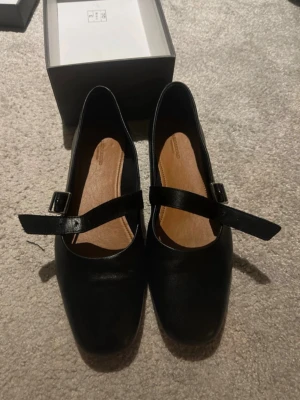 Svarta ballerinaskor från Vagabond - Stilrena svarta ballerinaskor från Vagabond med fyrkantig tå och justerbart spänne över foten. Skorna är i slätt läder och har en klassisk design som passar till många olika outfits. Bekväm innersula i ljust läder för extra komfort.