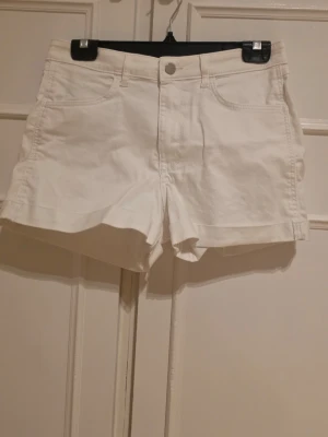 Vita shorts med fickor - Klassiska vita shorts i bomull med normal passform. Shortsen har två framfickor, bälteshällor och stängs med knapp och dragkedja.