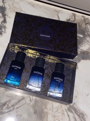 Dior Sauvage parfymset 3x30ml - Exklusivt parfymset från Dior med tre flaskor Sauvage i snygga blåtonade glasflaskor. Setet innehåller Eau de Parfum, Eau de Toilette och Parfum, alla på 30 ml vardera. Kommer i en elegant mörkblå presentask med gulddetaljer.